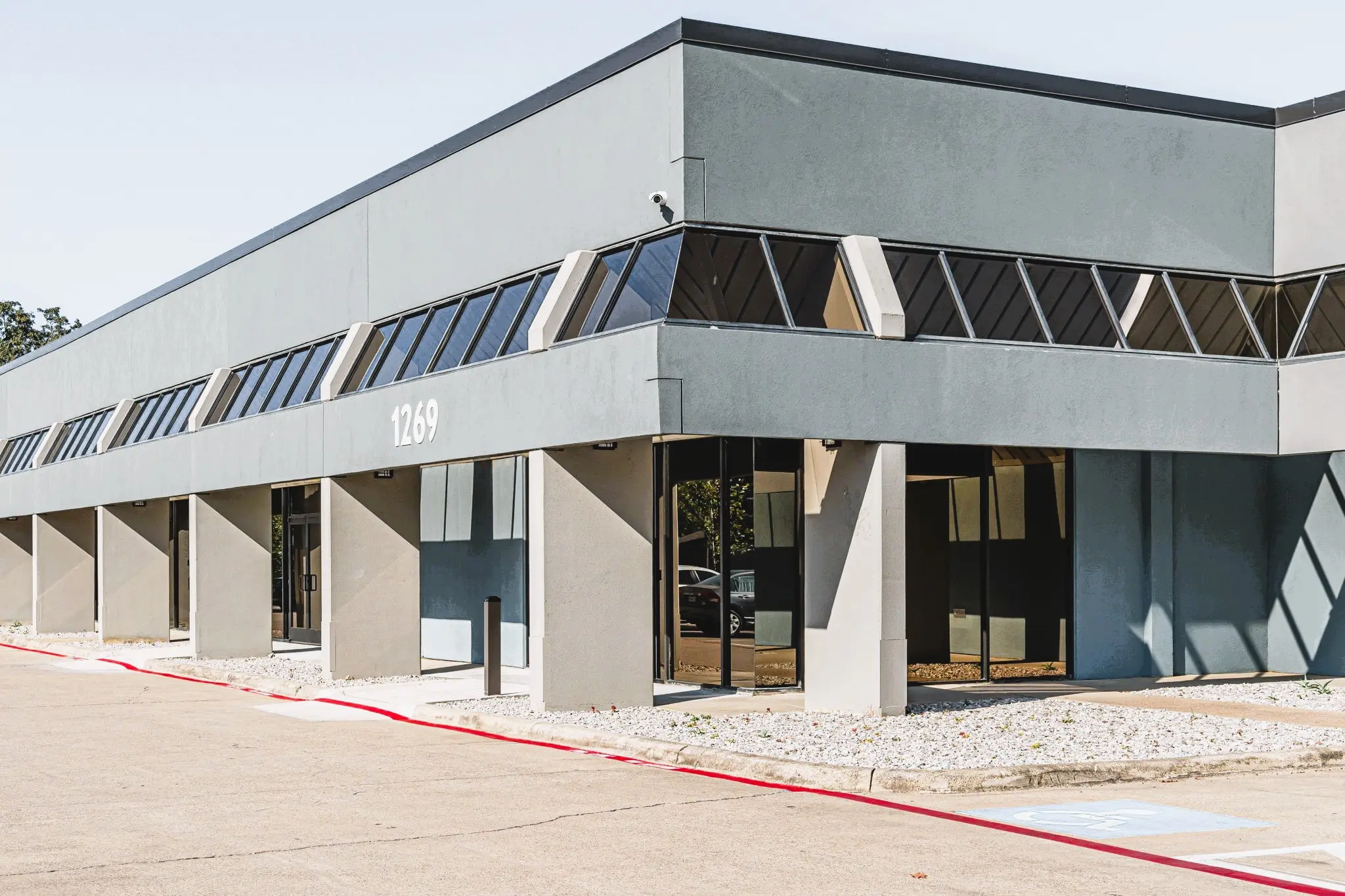 Two-story gray commercial building with glass entrance and the address 1269 displayed above the doors