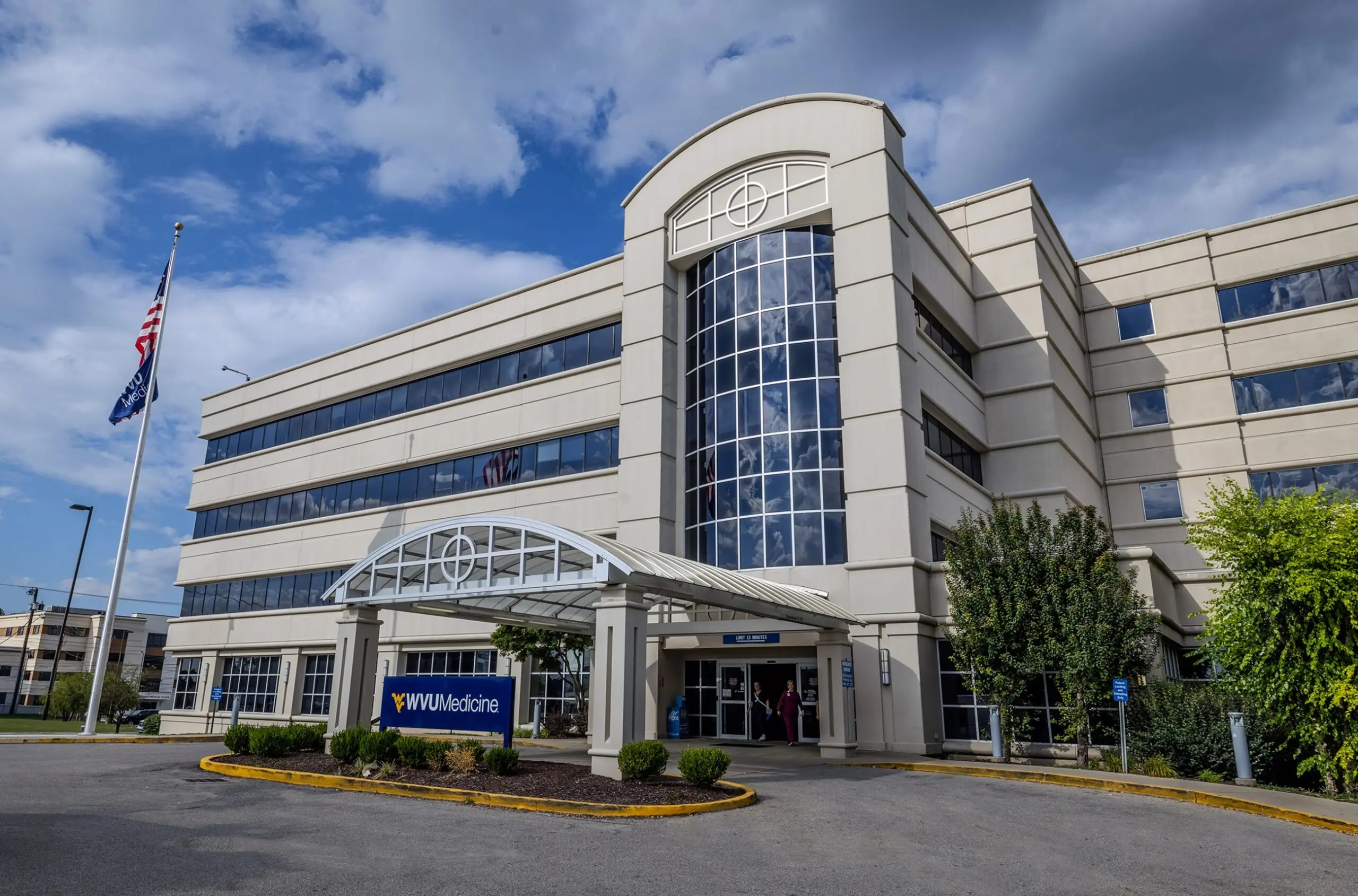 Multi-story beige hospital building with a WVU Medicine sign and covered entrance