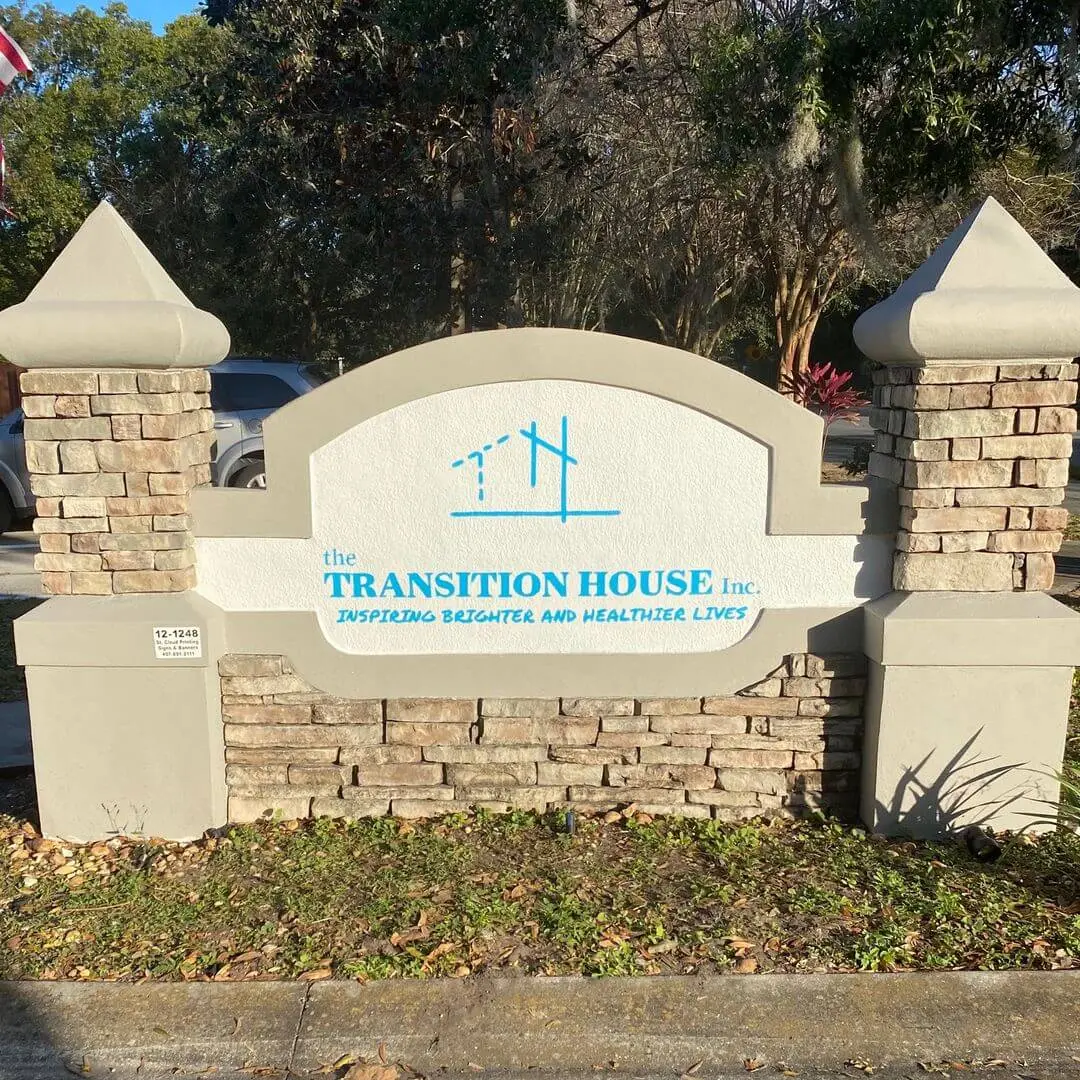 Entrance sign reading the TRANSITION HOUSE Inc. with the tagline Inspiring Brighter and Healthier Lives