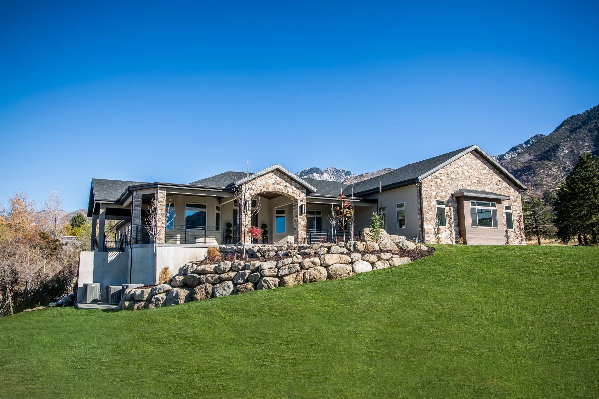 Stone and stucco single-story building with a green lawn and mountain backdrop