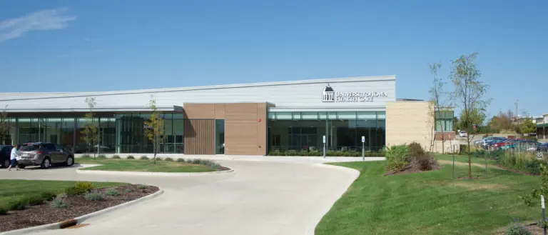 One-story modern University of Iowa Health Care building with glass entrance and landscaped drive