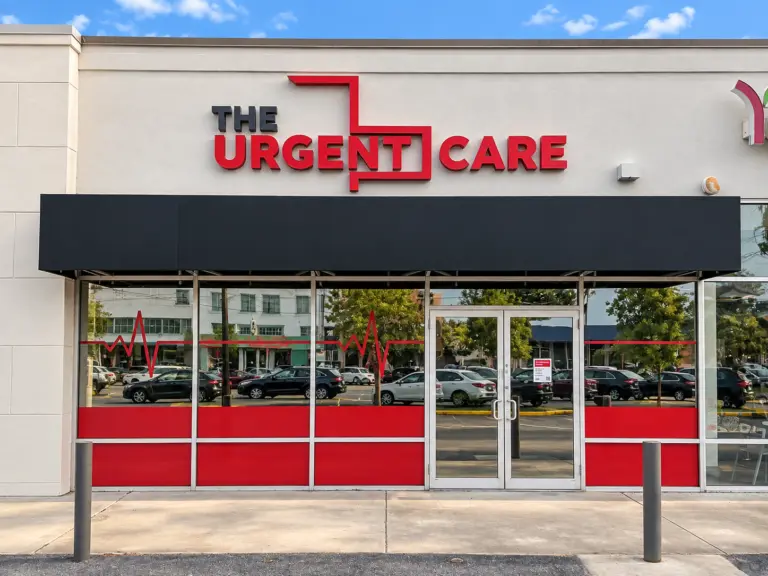 Storefront with a black awning and a red and black 'THE URGENT CARE' sign on a light building