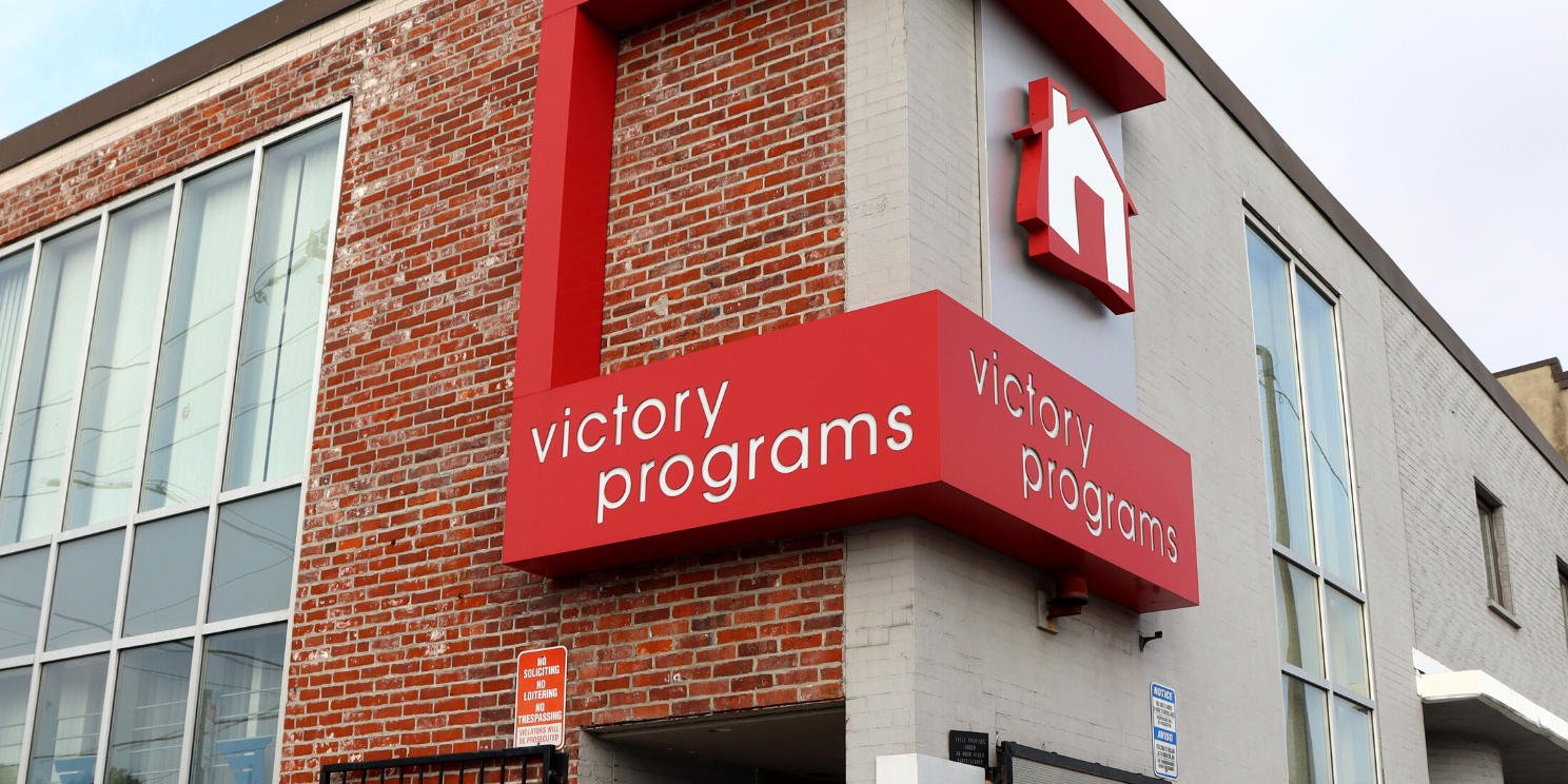 Brick building with a red Victory Programs sign and house logo above the entrance