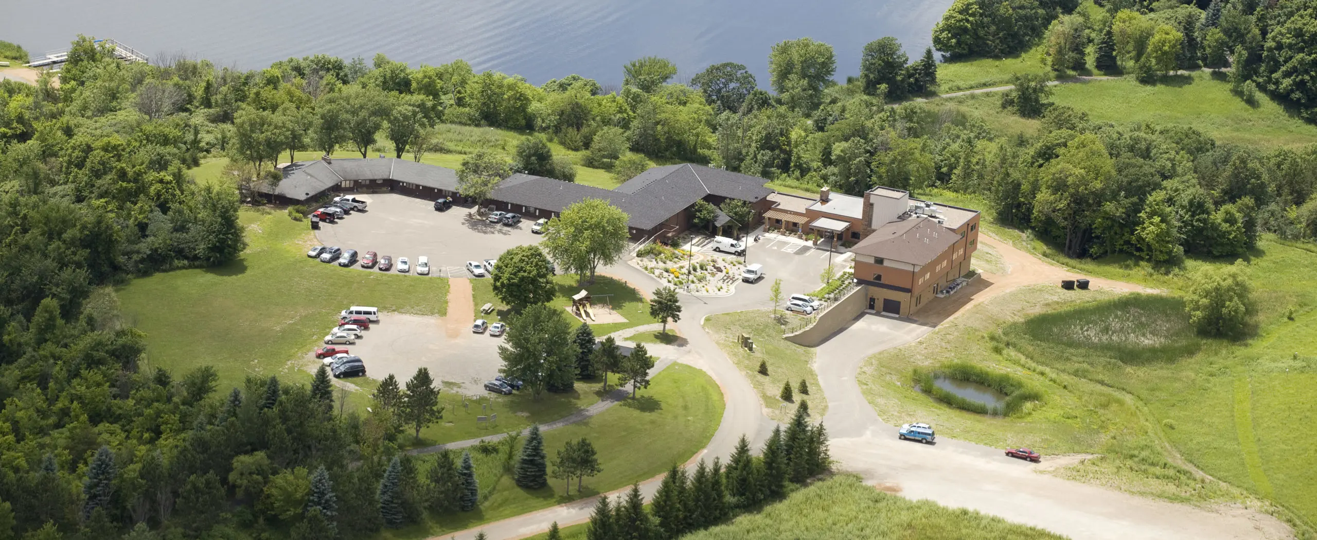 Aerial view of Vinland National Center's brick and wood buildings, parking and grounds beside a lake