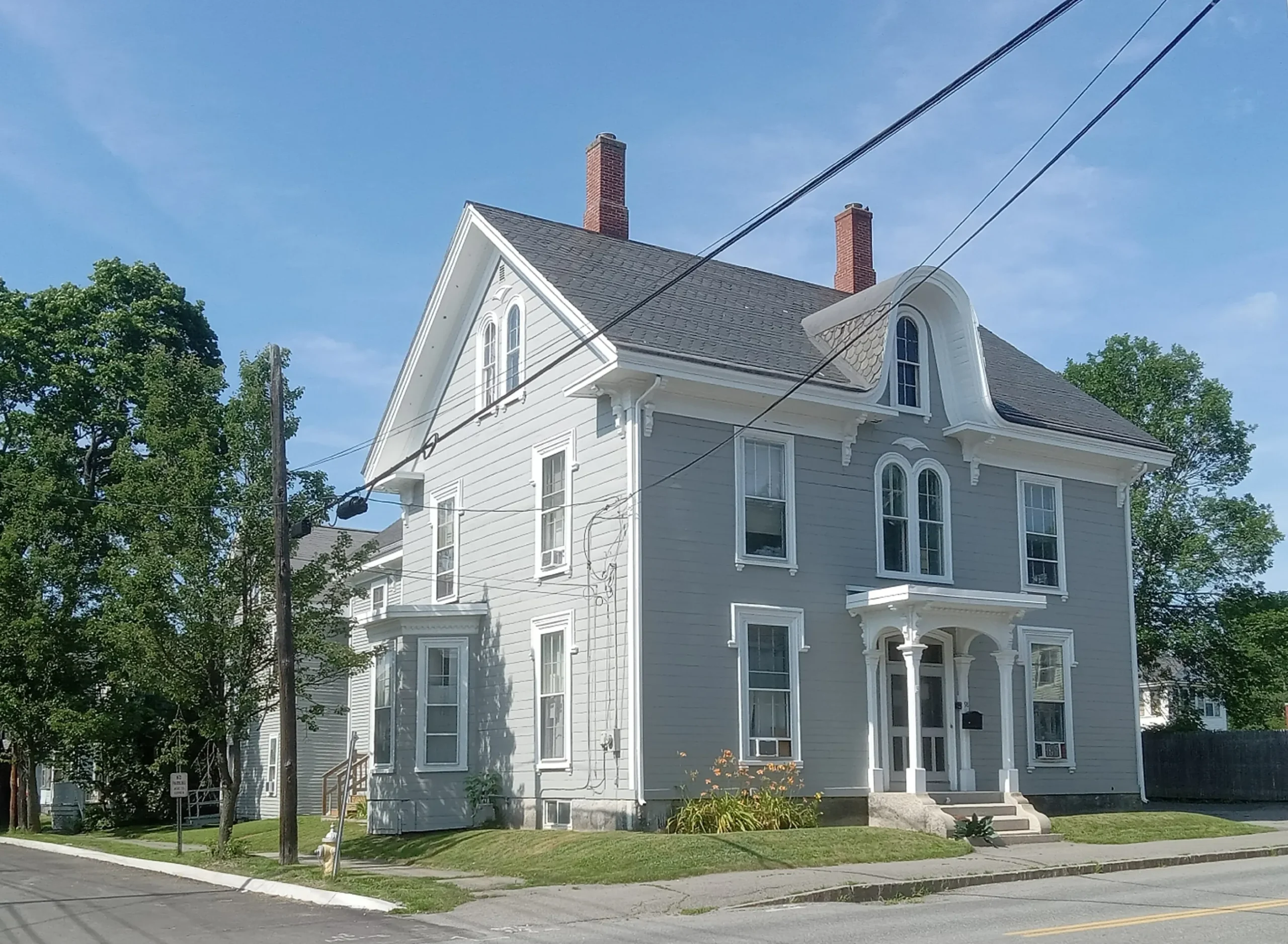 Two-story gray house with white trim, a covered front entrance and a green lawn